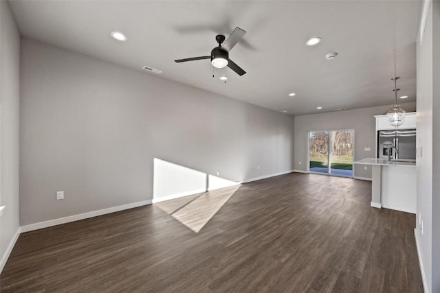 unfurnished living room featuring ceiling fan and dark wood-type flooring