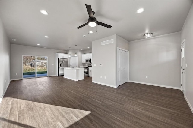 unfurnished living room with ceiling fan, sink, and dark wood-type flooring