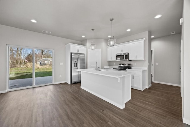 kitchen with white cabinetry, dark hardwood / wood-style flooring, decorative light fixtures, a kitchen island with sink, and appliances with stainless steel finishes