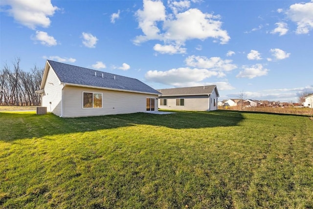 rear view of property featuring a lawn and central air condition unit