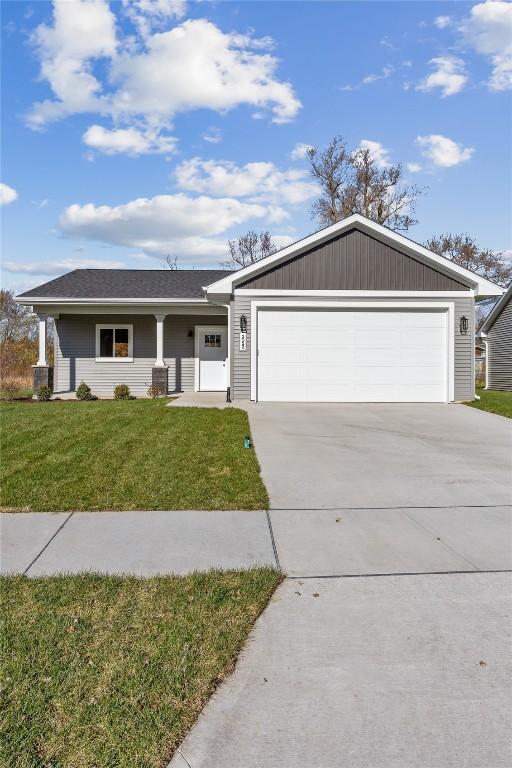 single story home with covered porch, a garage, and a front lawn