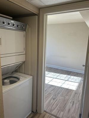 washroom featuring stacked washer and clothes dryer and light wood-type flooring