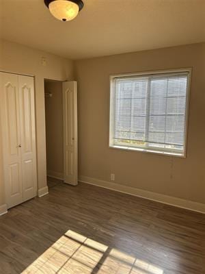 unfurnished bedroom with dark wood-type flooring and a closet