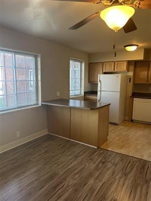 kitchen featuring ceiling fan, dark hardwood / wood-style flooring, white appliances, and kitchen peninsula