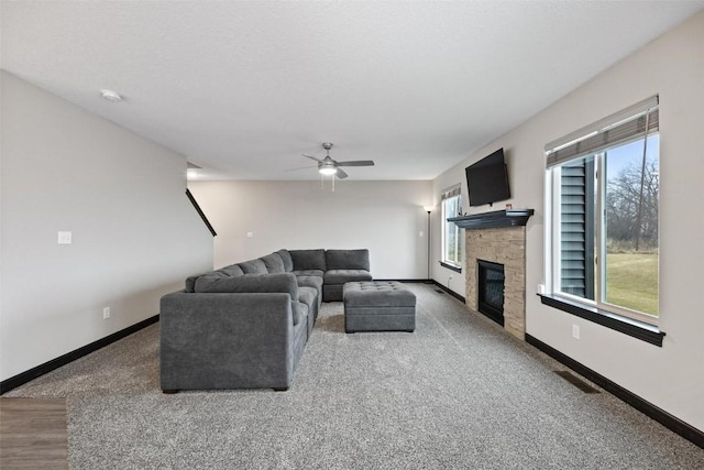 carpeted living room with ceiling fan and a fireplace