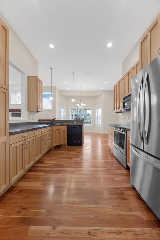 kitchen with an inviting chandelier, black appliances, hanging light fixtures, hardwood / wood-style flooring, and light brown cabinetry