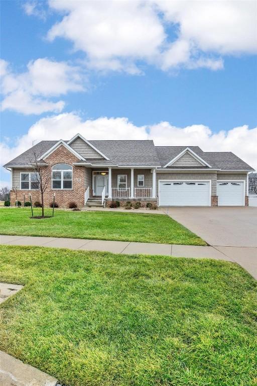 view of front of property featuring a porch, a garage, and a front lawn