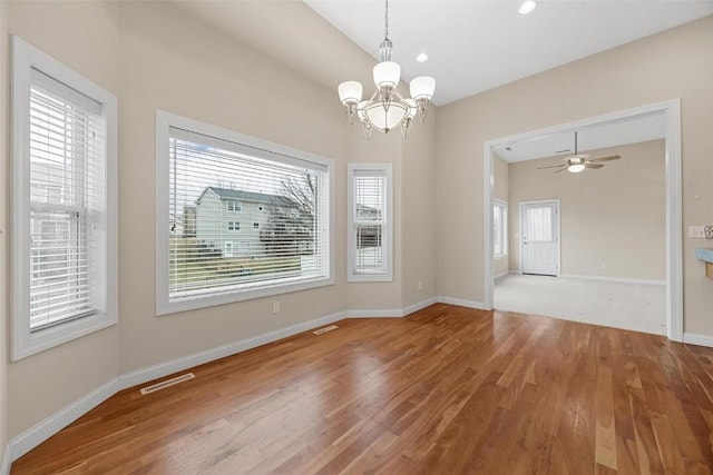 unfurnished room with hardwood / wood-style floors, ceiling fan with notable chandelier, and a healthy amount of sunlight