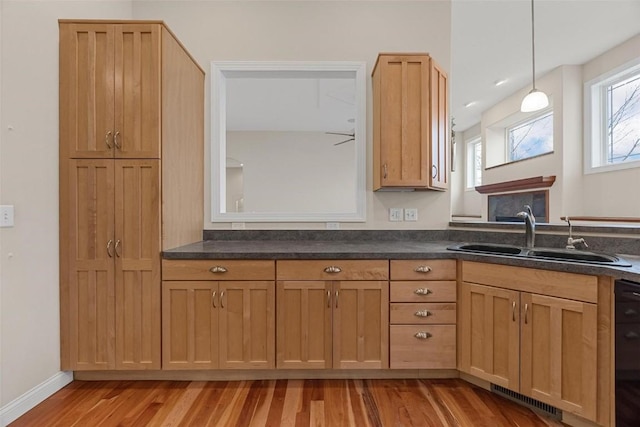 kitchen with ceiling fan, sink, decorative light fixtures, and light wood-type flooring