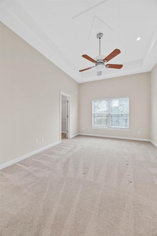 carpeted empty room featuring ceiling fan and a tray ceiling