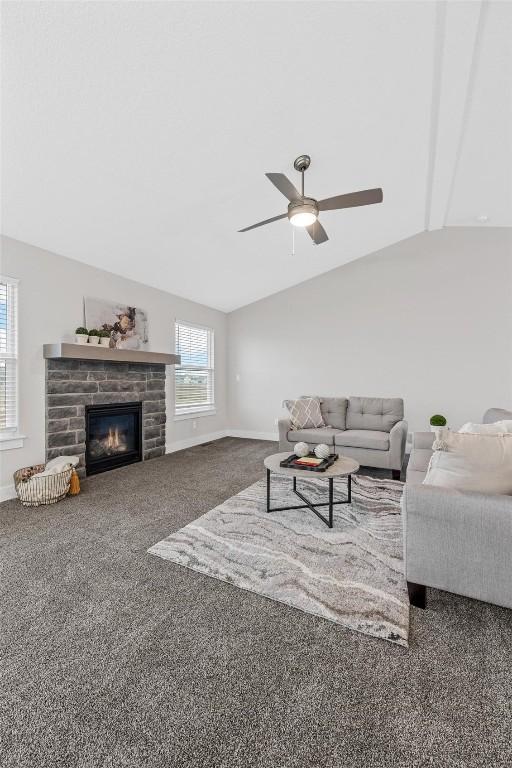 carpeted living room with ceiling fan, lofted ceiling with beams, and a fireplace