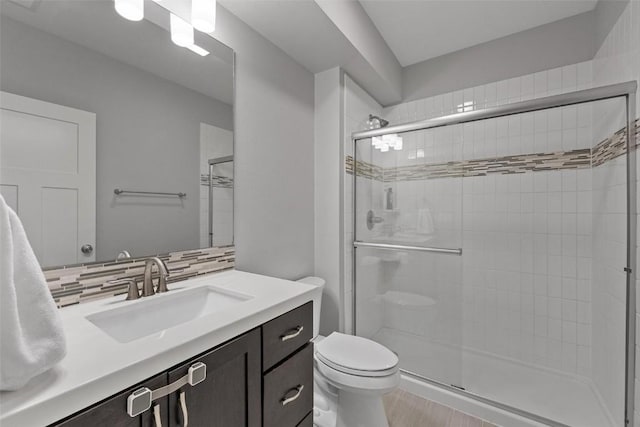 bathroom with decorative backsplash, toilet, walk in shower, and vanity