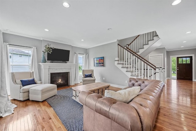 living room with a fireplace, light hardwood / wood-style floors, and ornamental molding