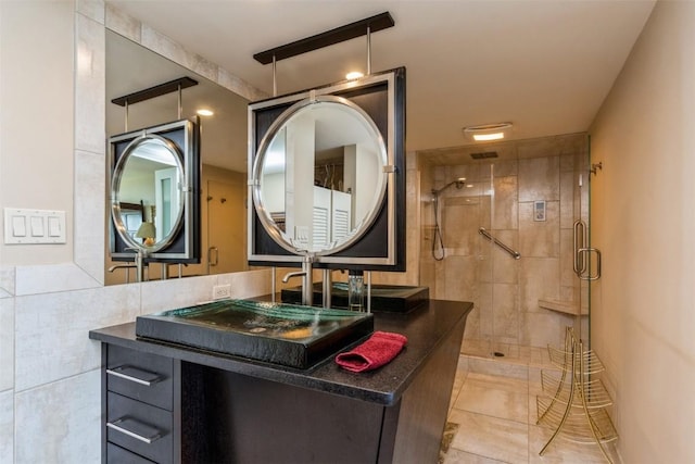 bathroom with tile patterned flooring, vanity, tile walls, and a shower with shower door