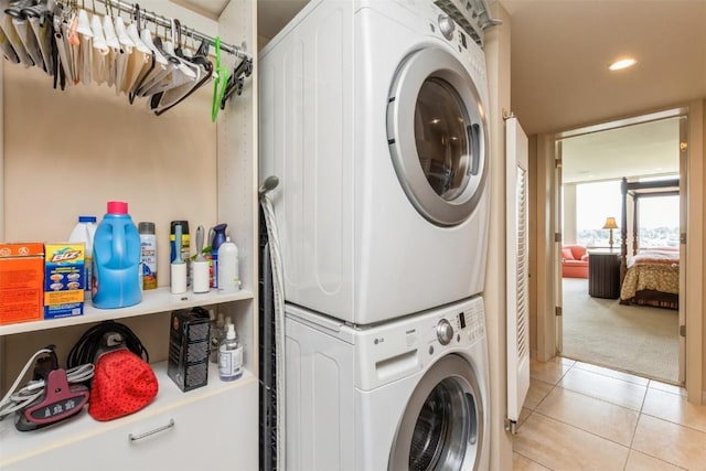 clothes washing area featuring light colored carpet and stacked washer and clothes dryer