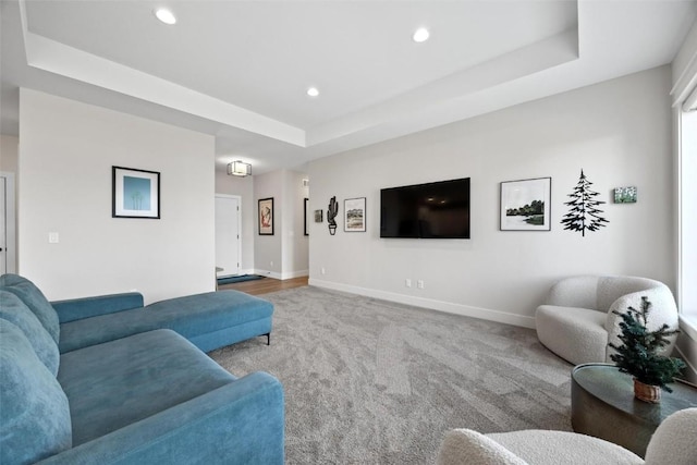 living room with a tray ceiling and light carpet