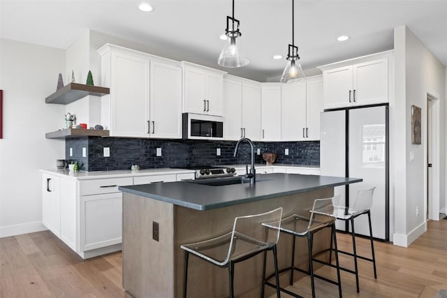 kitchen featuring white cabinets, white refrigerator, light hardwood / wood-style flooring, and a kitchen island with sink