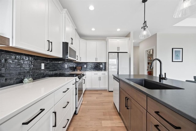 kitchen featuring backsplash, light wood-type flooring, stainless steel appliances, sink, and white cabinetry