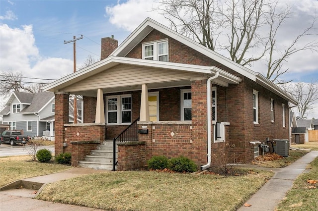 bungalow with covered porch, a front yard, and central air condition unit