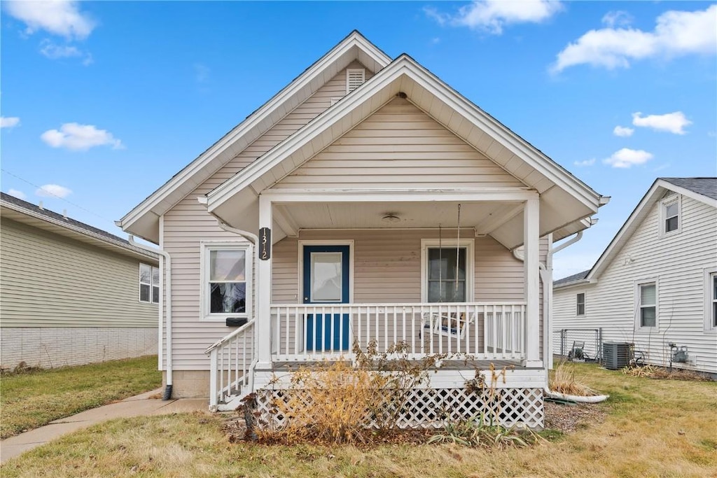 bungalow with covered porch, central AC unit, and a front yard