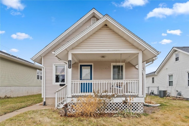 bungalow with covered porch, central AC unit, and a front yard