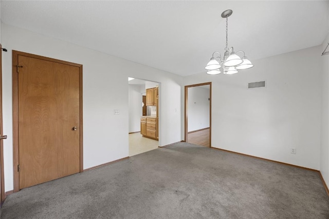 unfurnished room featuring a chandelier and light colored carpet