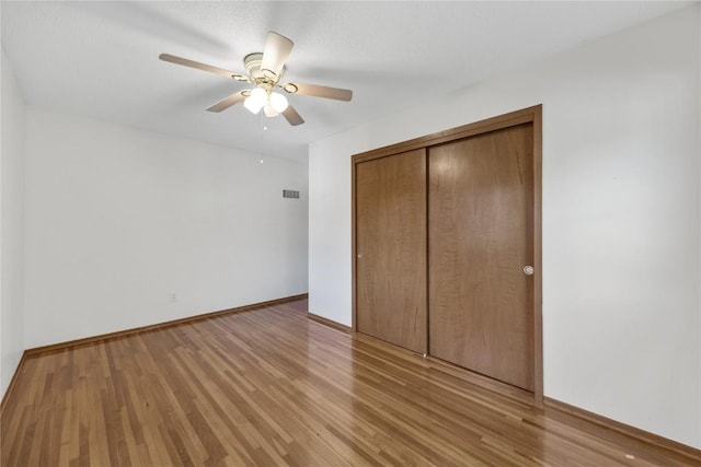 unfurnished bedroom featuring ceiling fan, light hardwood / wood-style floors, and a closet