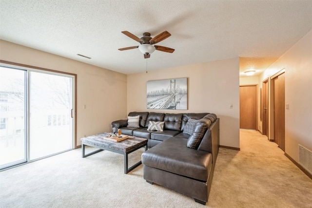 living room with a textured ceiling, ceiling fan, and light carpet