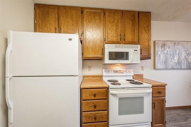 kitchen with hardwood / wood-style flooring, white appliances, and a textured ceiling