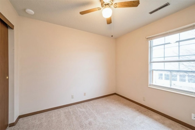 carpeted empty room featuring plenty of natural light and ceiling fan