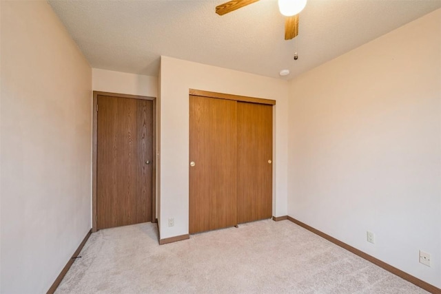 unfurnished bedroom featuring a textured ceiling, ceiling fan, and light carpet