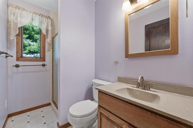 bathroom featuring vanity, a shower with shower door, and toilet