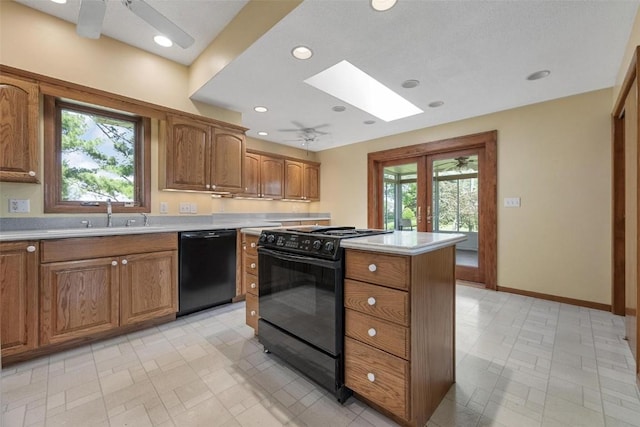 kitchen with a skylight, ceiling fan, sink, black appliances, and a center island