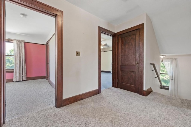 corridor featuring light carpet and vaulted ceiling