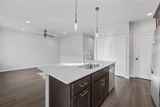 kitchen with appliances with stainless steel finishes, ceiling fan, sink, decorative light fixtures, and an island with sink