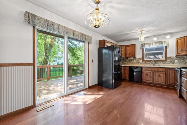 kitchen featuring decorative backsplash, sink, black appliances, decorative light fixtures, and an inviting chandelier