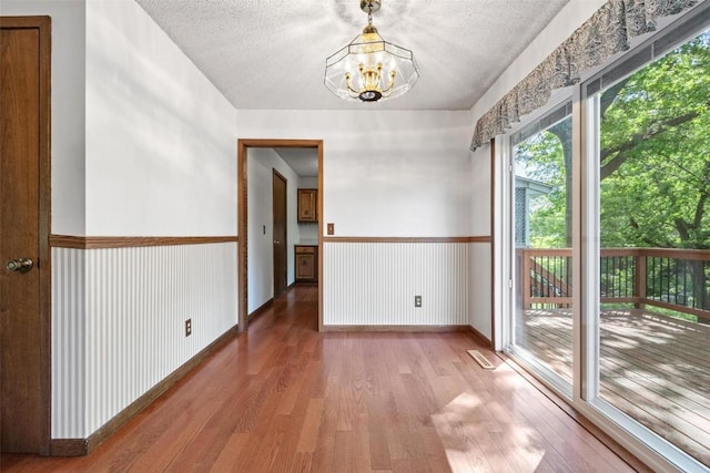 spare room featuring hardwood / wood-style floors, a textured ceiling, and a notable chandelier