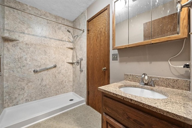 bathroom with vanity, a shower, and a textured ceiling