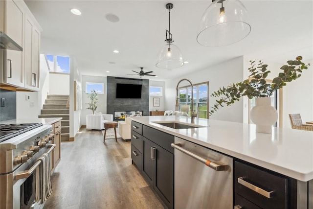 kitchen with white cabinetry, sink, ceiling fan, stainless steel appliances, and a kitchen island with sink