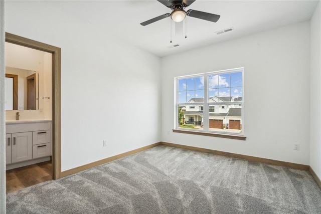 unfurnished bedroom featuring ceiling fan, carpet floors, sink, and ensuite bath