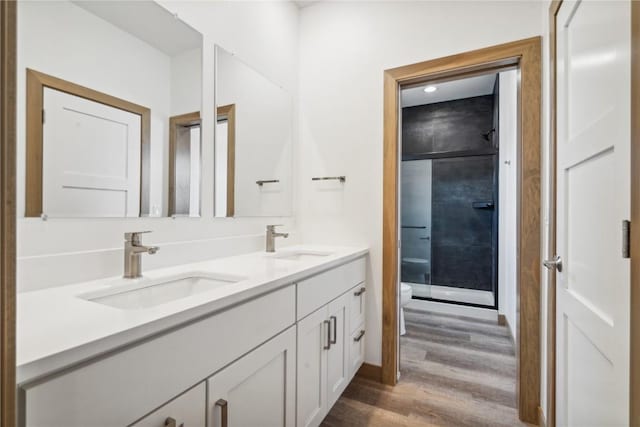 bathroom with a shower, vanity, hardwood / wood-style flooring, and toilet