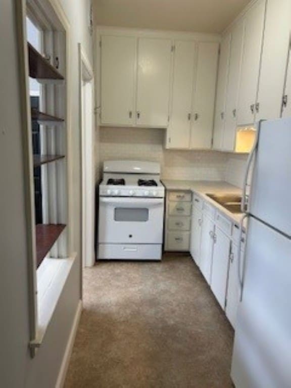 kitchen with white cabinetry, sink, and white appliances