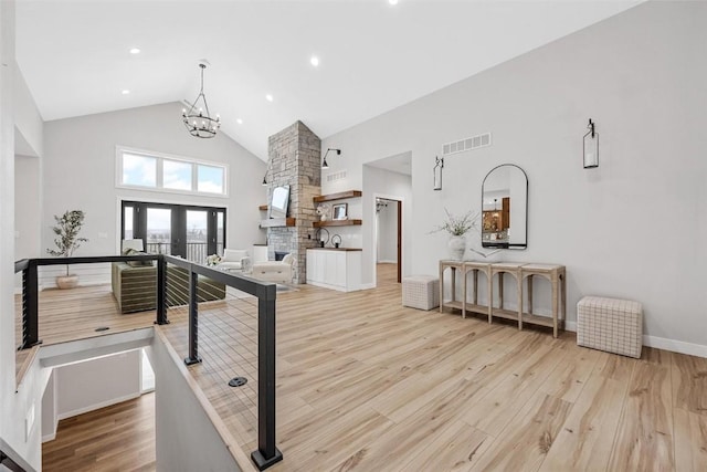 interior space featuring a chandelier, french doors, high vaulted ceiling, and light hardwood / wood-style floors