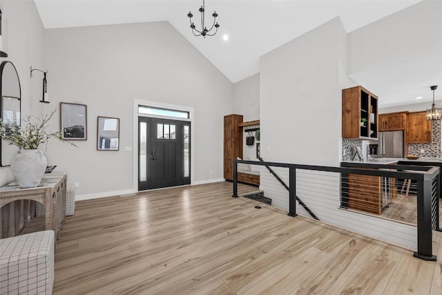 entrance foyer with high vaulted ceiling, light hardwood / wood-style floors, and a notable chandelier