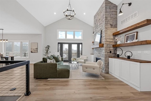 living room featuring a wealth of natural light, a fireplace, light wood-type flooring, and a notable chandelier