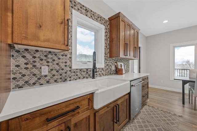 kitchen featuring dishwasher, decorative backsplash, sink, and light hardwood / wood-style flooring