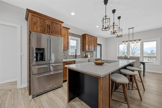 kitchen featuring a wealth of natural light, high end fridge, pendant lighting, a breakfast bar, and a kitchen island