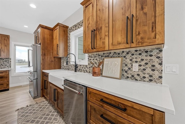 kitchen featuring decorative backsplash, sink, light hardwood / wood-style flooring, and appliances with stainless steel finishes