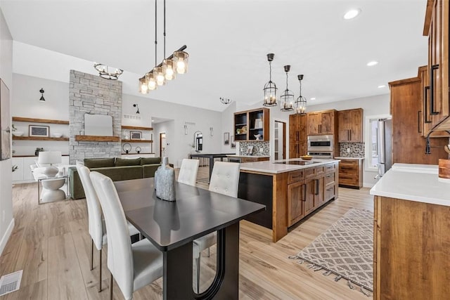 kitchen with sink, hanging light fixtures, a kitchen island with sink, and tasteful backsplash