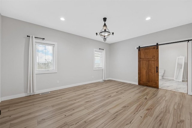 spare room featuring a barn door and light wood-type flooring